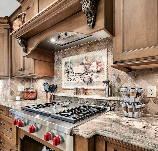 kitchen featuring stainless steel range, custom exhaust hood, light stone countertops, and decorative backsplash