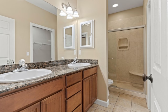 bathroom featuring tile patterned flooring, vanity, toilet, and a shower with shower door