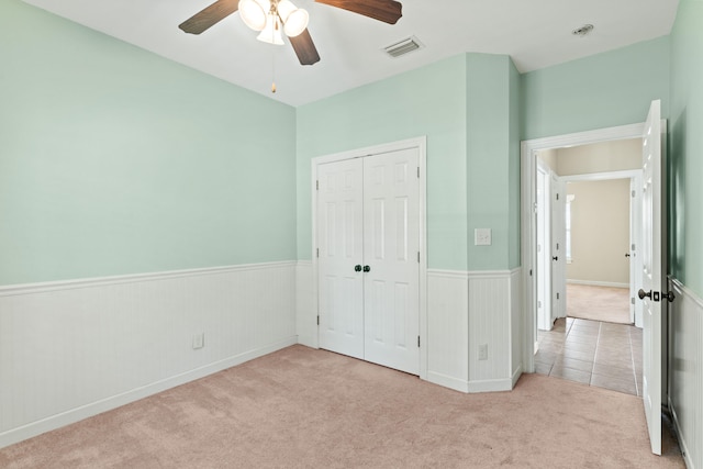 unfurnished bedroom featuring ceiling fan, light colored carpet, and a closet