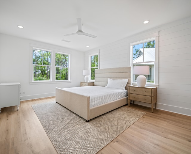 bedroom with ceiling fan, light wood-type flooring, and multiple windows