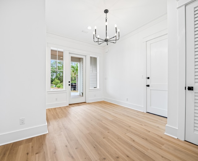 unfurnished dining area with ornamental molding, light hardwood / wood-style flooring, and a chandelier