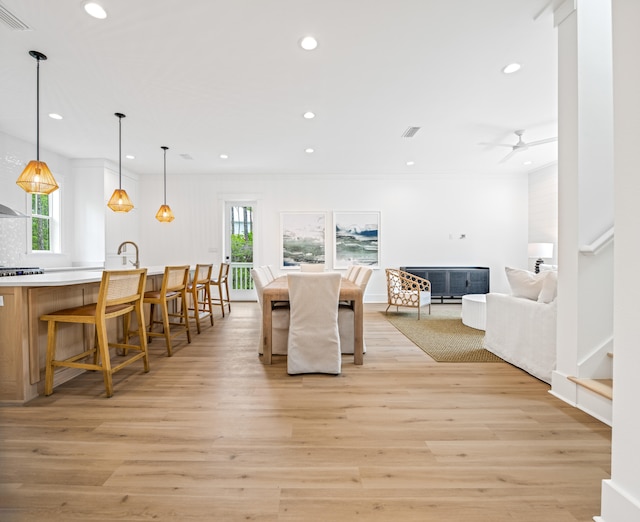 dining area featuring ceiling fan, light wood-type flooring, and crown molding