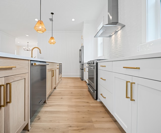 kitchen featuring light wood-type flooring, hanging light fixtures, wall chimney range hood, backsplash, and appliances with stainless steel finishes