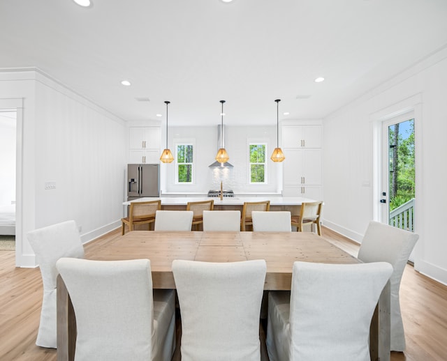 dining space with light wood-type flooring, crown molding, and a wealth of natural light