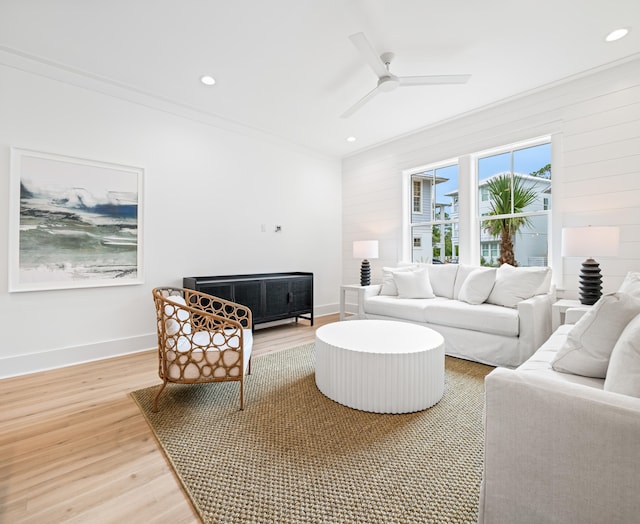 living room with wood-type flooring, ornamental molding, and ceiling fan