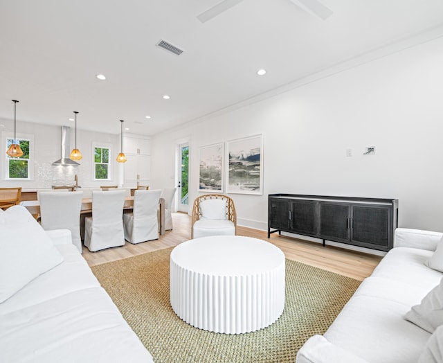 living room featuring ceiling fan, light hardwood / wood-style flooring, and crown molding