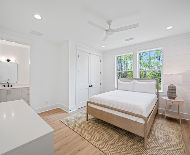 bedroom featuring light hardwood / wood-style flooring, connected bathroom, ceiling fan, and sink