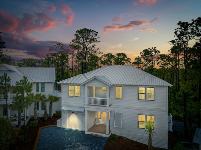 back house at dusk with a balcony and a garage