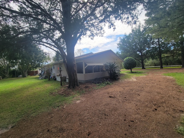 view of side of property with a sunroom and a lawn