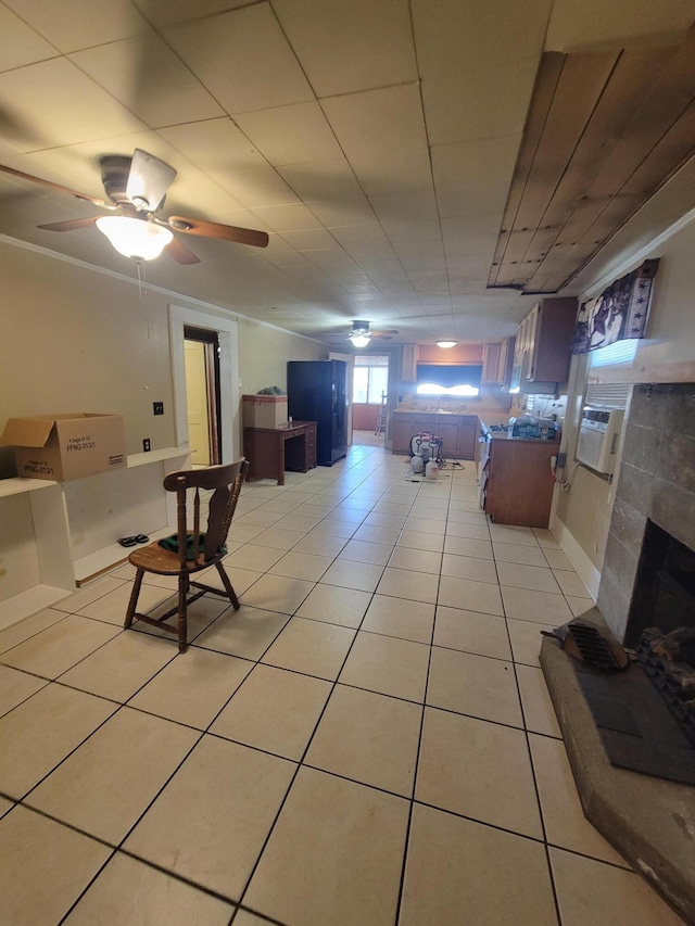 living room featuring a tiled fireplace, light tile patterned floors, and ceiling fan