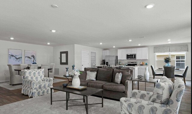 living area featuring a textured ceiling, wood finished floors, visible vents, and recessed lighting