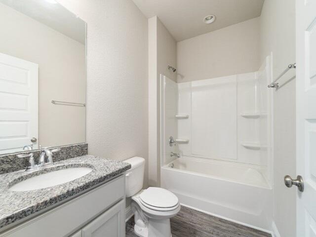 full bathroom featuring toilet, vanity, wood finished floors, and shower / bathtub combination