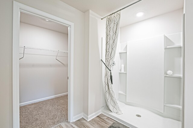 bathroom featuring a stall shower, a spacious closet, and baseboards