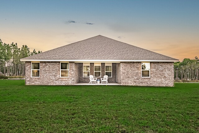 rear view of house featuring a patio area, brick siding, and roof with shingles