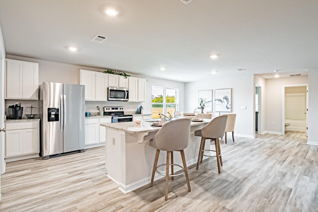 kitchen featuring an island with sink, white cabinetry, and stainless steel appliances