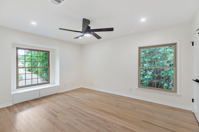 empty room featuring ceiling fan, light hardwood / wood-style flooring, and a wealth of natural light