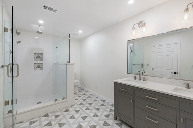 bathroom featuring a shower with door, toilet, and vanity