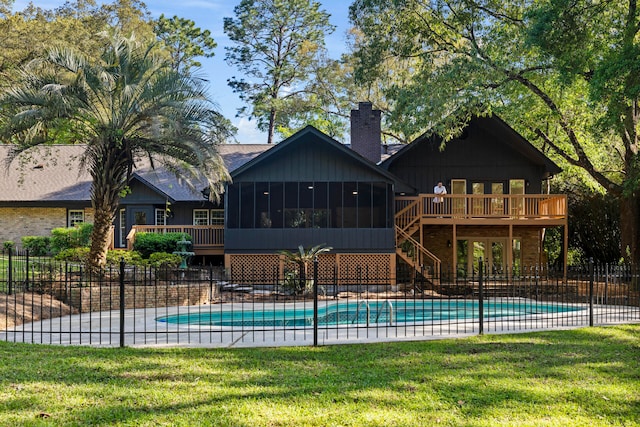 view of pool with a sunroom, a deck, and a lawn