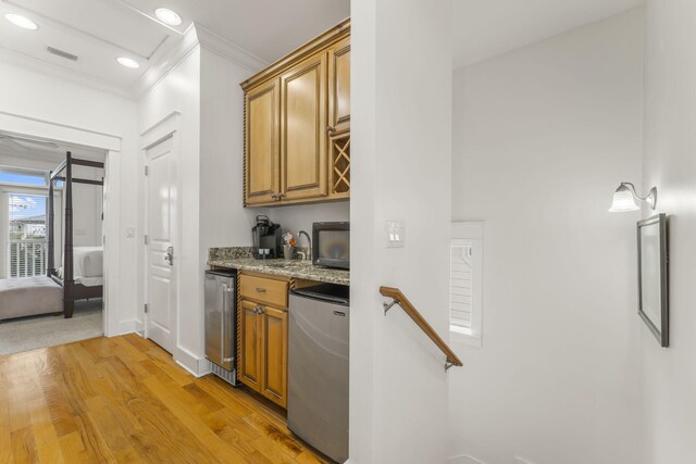 kitchen with light stone counters, refrigerator, visible vents, light wood-style floors, and ornamental molding