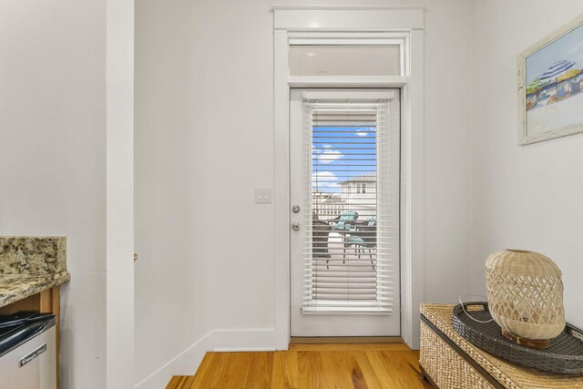 doorway featuring light wood finished floors and baseboards