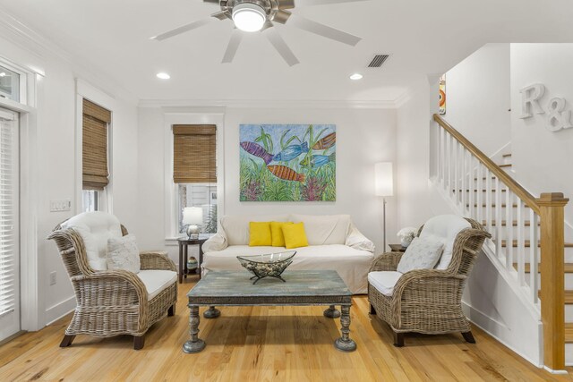 living area with ceiling fan, recessed lighting, wood finished floors, stairway, and crown molding