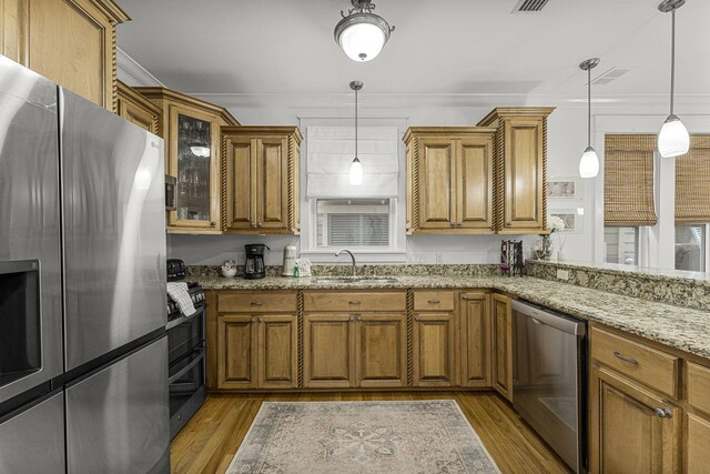 kitchen featuring brown cabinetry, ornamental molding, stainless steel refrigerator with ice dispenser, and a sink