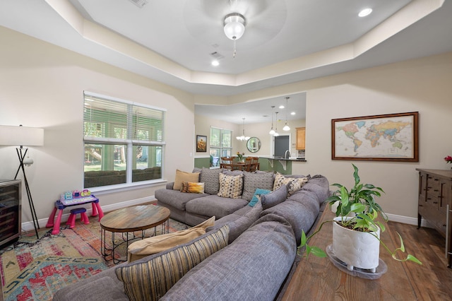 living room with ceiling fan, hardwood / wood-style flooring, and a tray ceiling