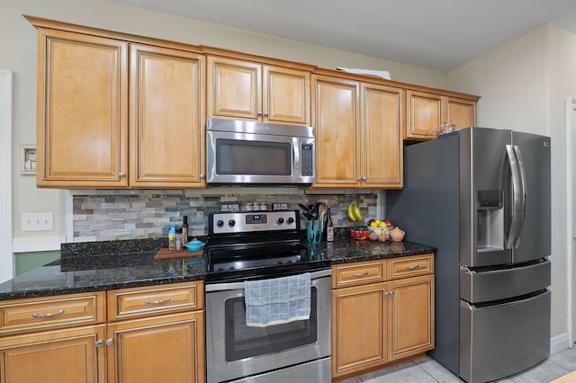 kitchen featuring stainless steel appliances, backsplash, light tile patterned floors, and dark stone counters