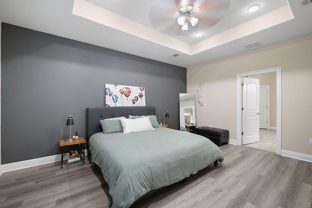 bedroom with a tray ceiling, hardwood / wood-style floors, and ceiling fan