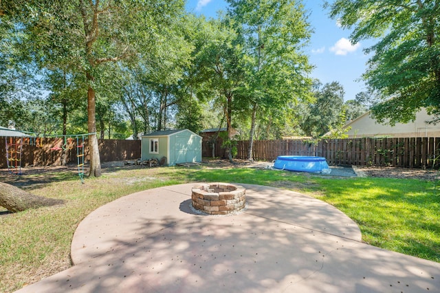 view of patio / terrace featuring a storage unit, a pool, and an outdoor fire pit