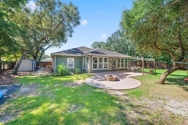 back of house with a shed, a lawn, a patio, and a fire pit