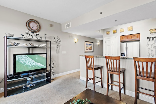 interior space featuring a breakfast bar area, stainless steel refrigerator with ice dispenser, and light carpet