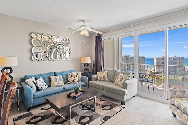 living room with ceiling fan, light colored carpet, and a water view