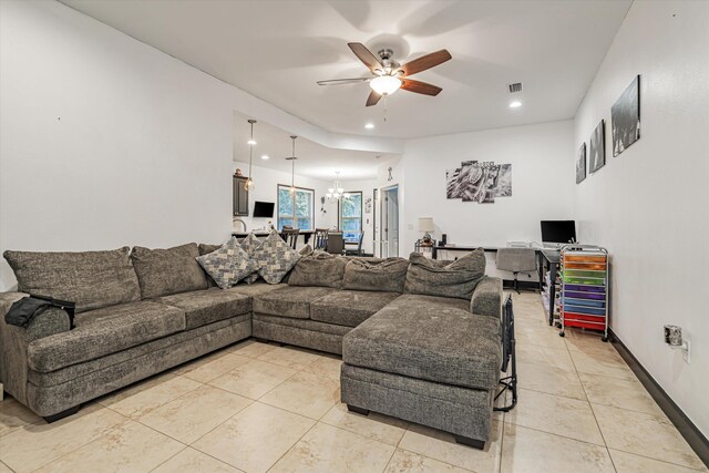 tiled living room with ceiling fan with notable chandelier