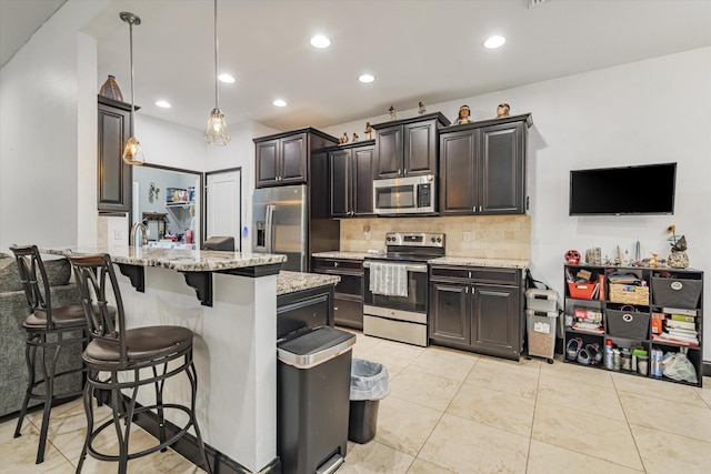 kitchen with light stone counters, light tile patterned floors, kitchen peninsula, decorative light fixtures, and stainless steel appliances