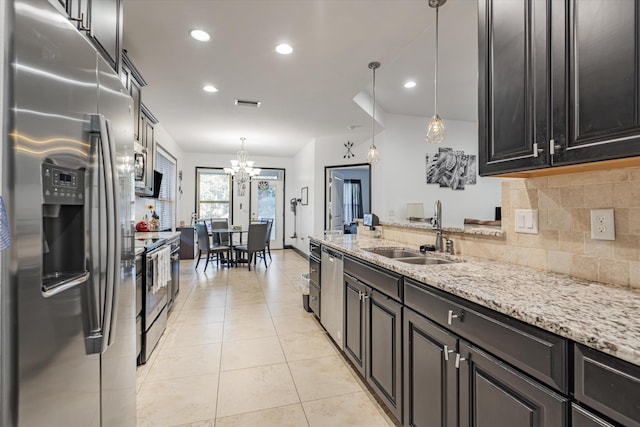 kitchen with hanging light fixtures, sink, a chandelier, stainless steel appliances, and decorative backsplash