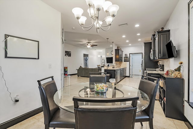 tiled dining space featuring ceiling fan with notable chandelier and sink