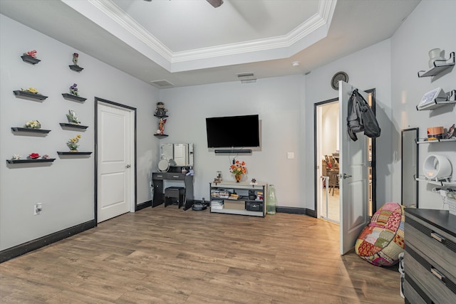 interior space with wood-type flooring, crown molding, and a raised ceiling