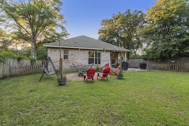 rear view of house featuring a lawn, a fire pit, and a patio area