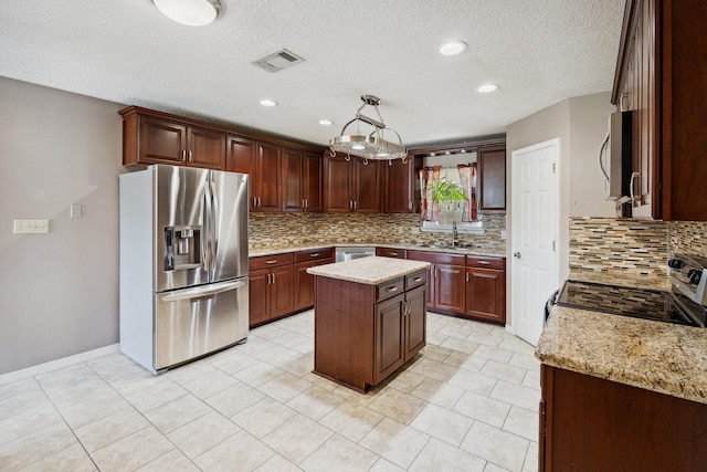 kitchen featuring a textured ceiling, stainless steel appliances, a center island, light stone countertops, and decorative backsplash