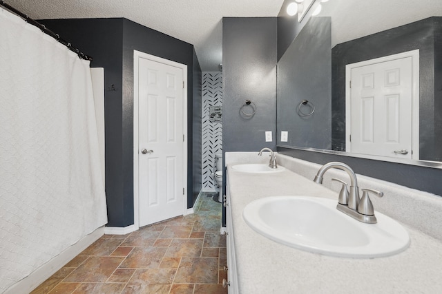 bathroom with a textured ceiling, vanity, and toilet