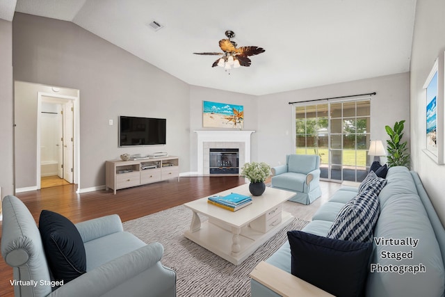 living room featuring wood-type flooring, a fireplace, vaulted ceiling, and ceiling fan