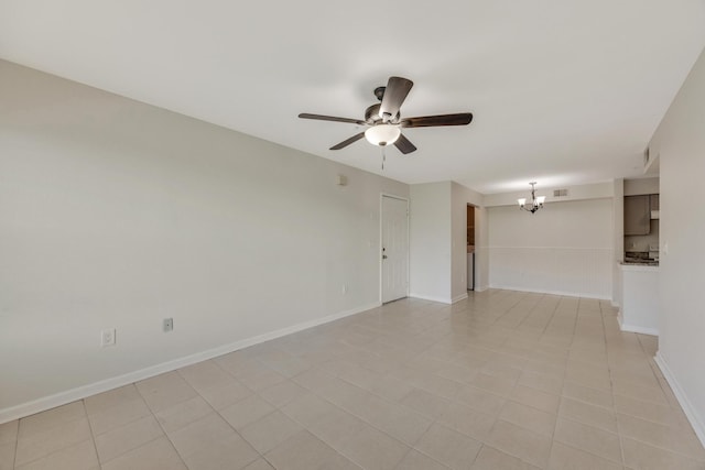 tiled empty room featuring ceiling fan with notable chandelier