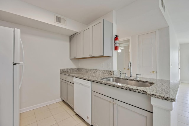 kitchen with light stone counters, light tile patterned flooring, sink, kitchen peninsula, and white appliances