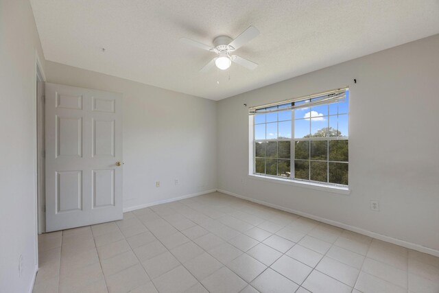 empty room with a textured ceiling, light tile patterned floors, and ceiling fan