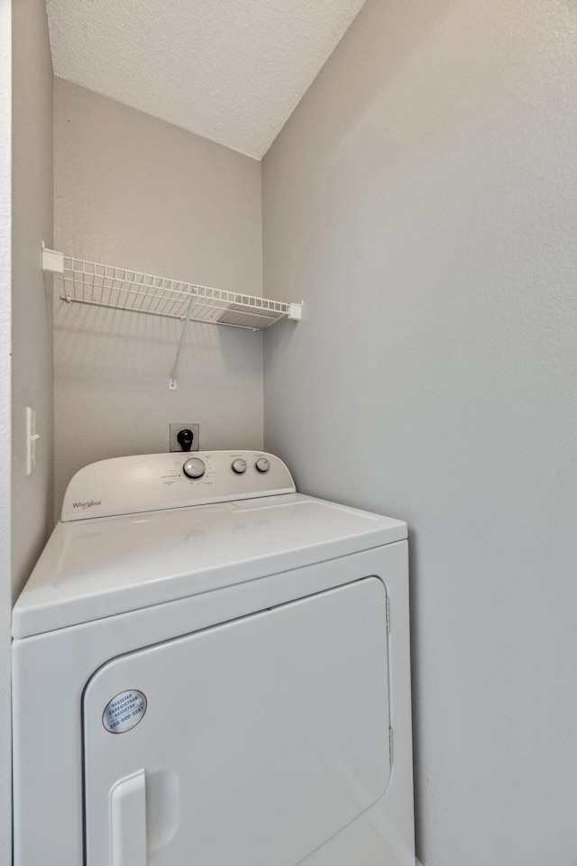 clothes washing area with washer / clothes dryer and a textured ceiling