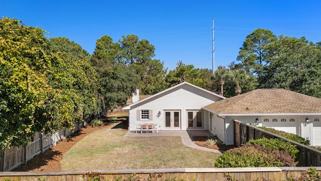 back of house with french doors, fence, brick siding, an attached garage, and a yard
