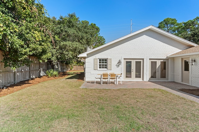 rear view of house featuring a patio, a lawn, and french doors