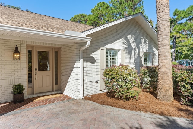 property entrance with brick siding and roof with shingles
