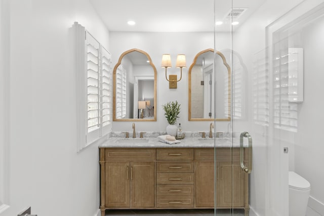 full bathroom with visible vents, a sink, double vanity, and toilet